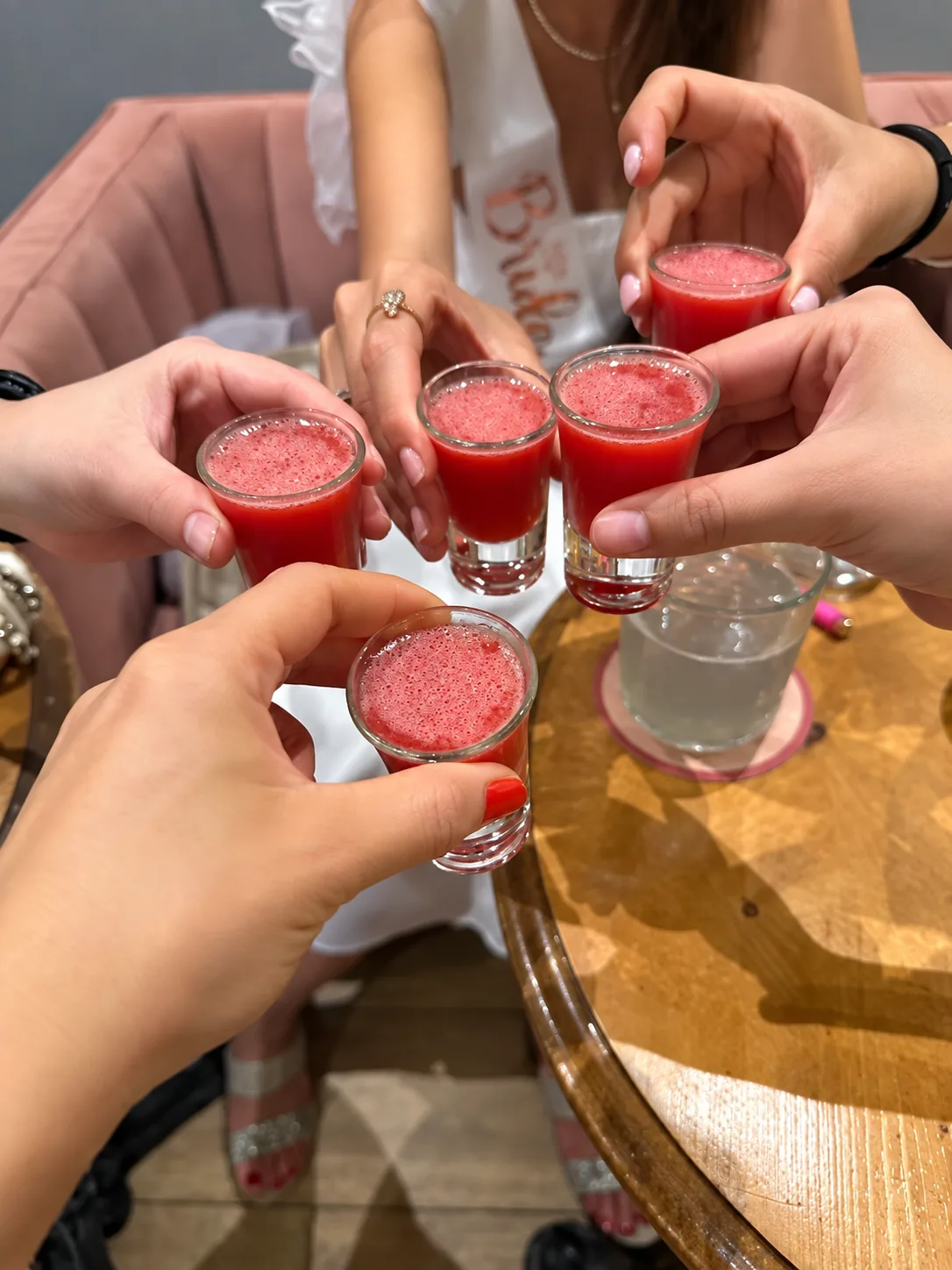 Hands raising five shot glasses in a toast, retouched photograph